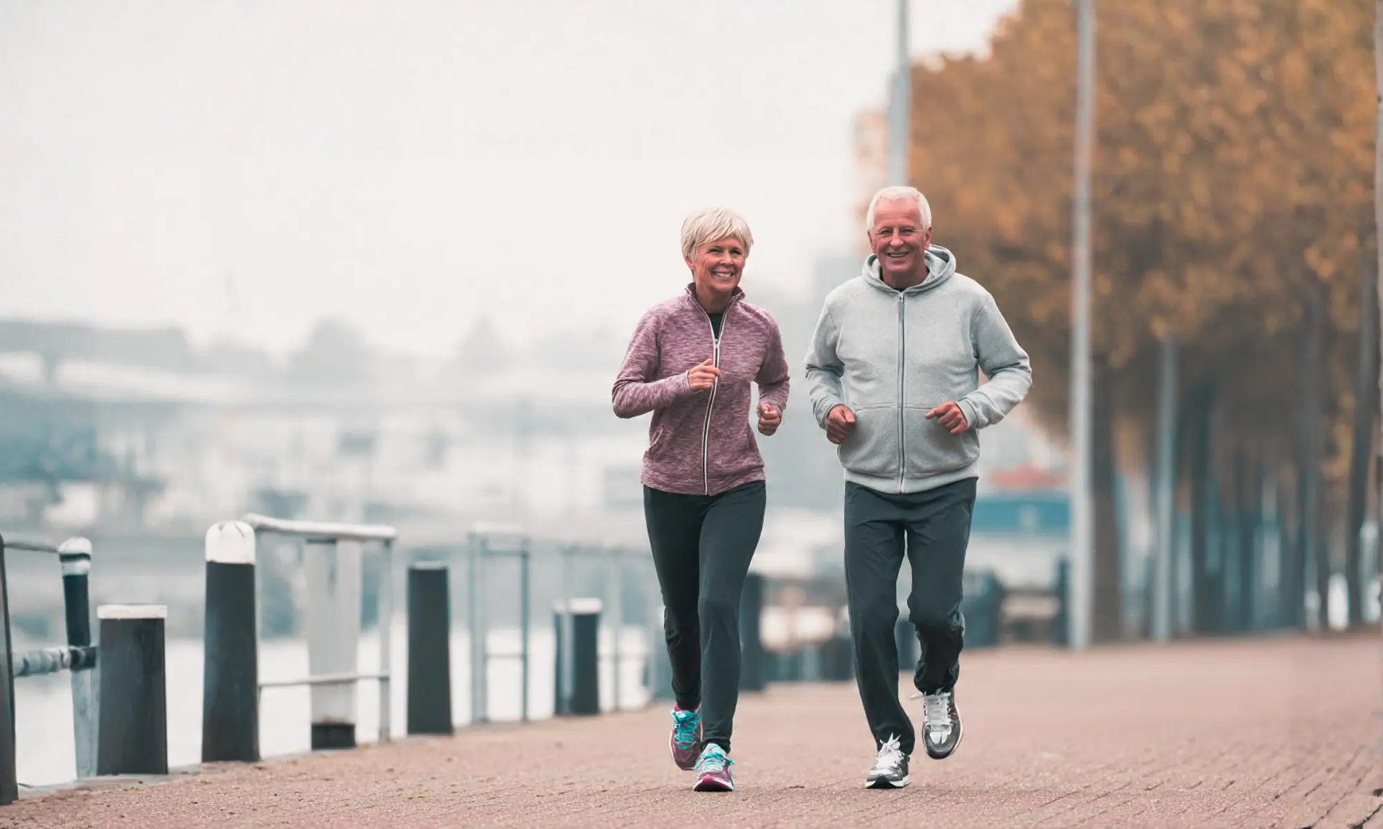 Two people jogging together outdoors along a waterfront path