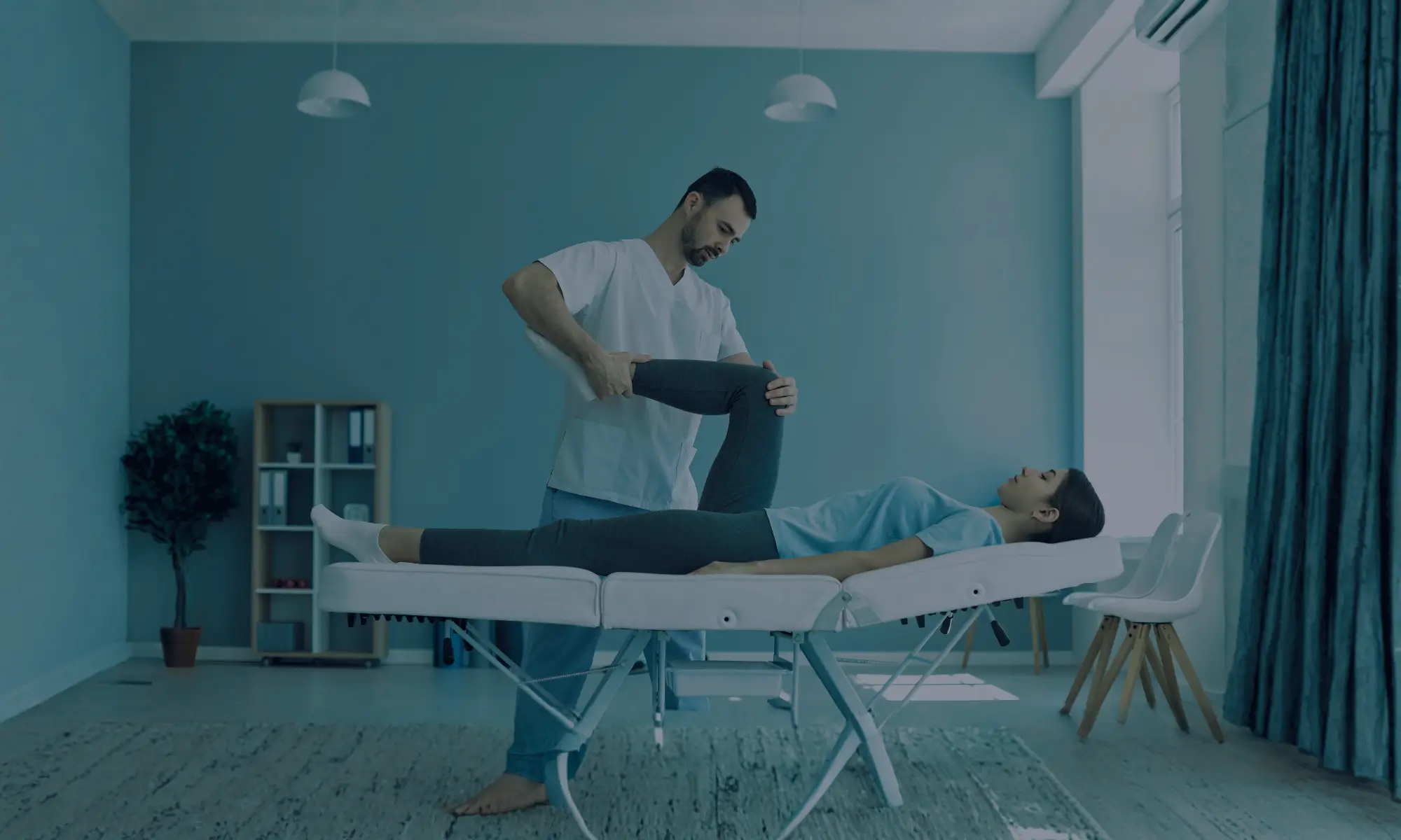Physical therapist assisting a person with leg movement on a treatment table